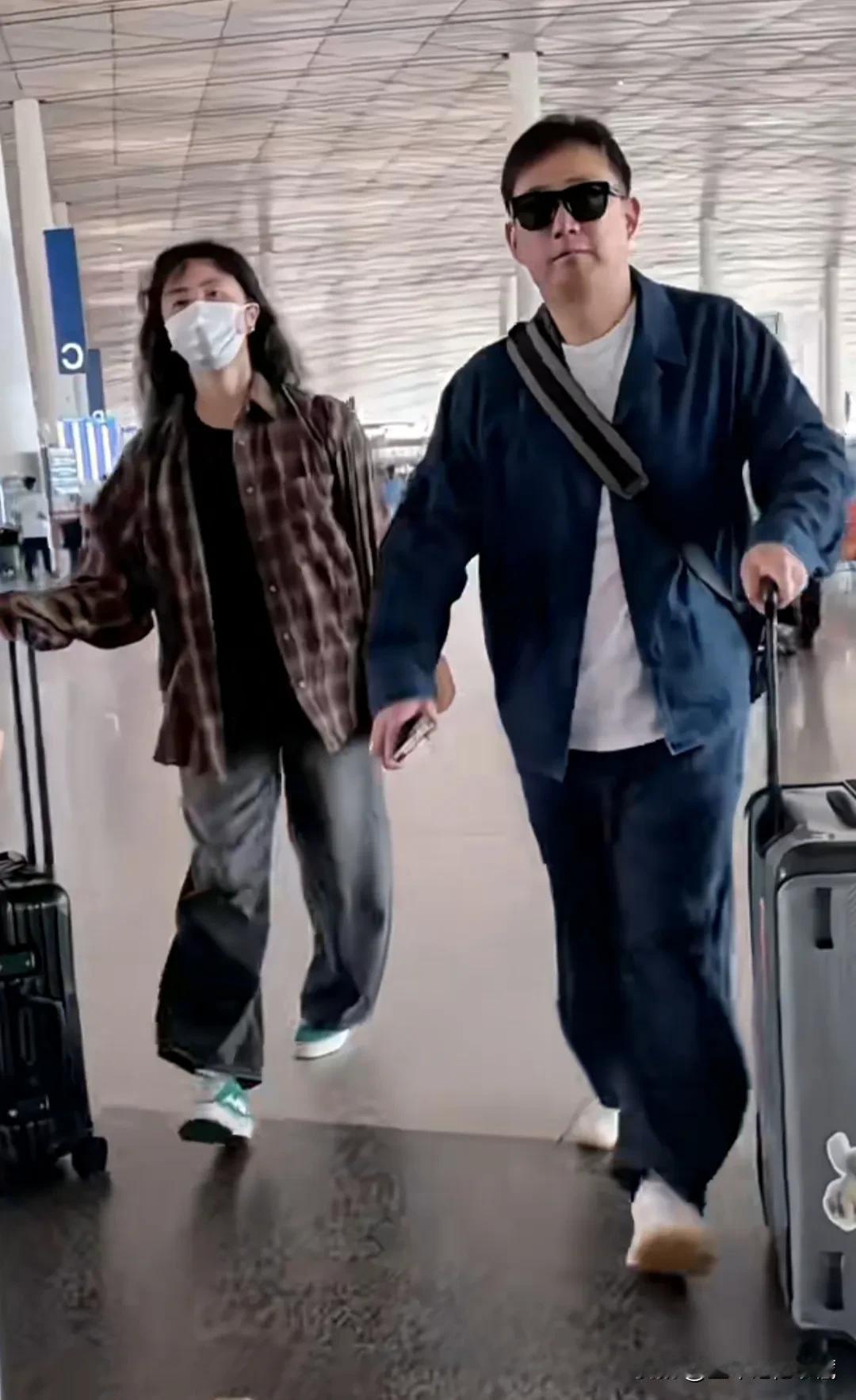 著名演员黄磊带妻子孙莉走机场大秀恩爱，黄磊发福了，脸型身材圆润，一身藏蓝色夹克外