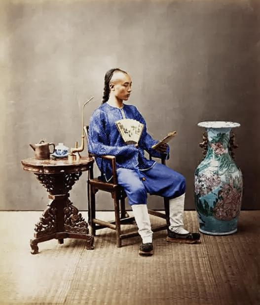 这是一张清代的室内摆拍照片，主角正是一位自带儒雅气质的古董商人。他留着清代典型