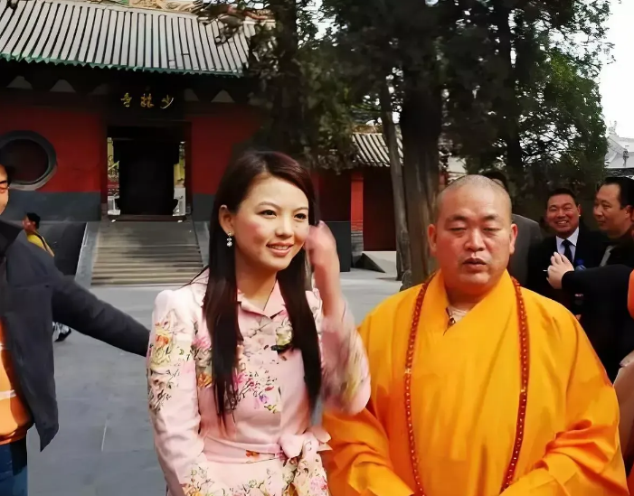 当年李湘去少林寺采访释永信，俩人合影那张照片，你还记得吗？镜头里她一身粉裙黑丝