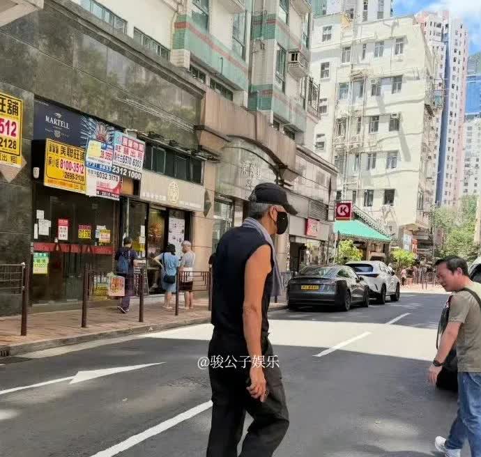 周润发近日在香港亲自驾车去某面馆吃面被网友偶遇，他穿着黑色无袖小汗衫，戴着口罩和