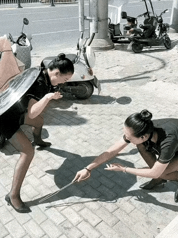 艳阳高照，两名女子闲的蛋疼。一名女子背着一只大锅盖利用阳光的投影扮乌龟，另一名女