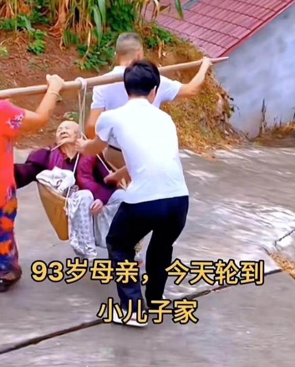 93岁老人有8儿2女，这次轮到小儿子家住，小儿子和儿媳拿着扁担将老人放入萝筐挑回