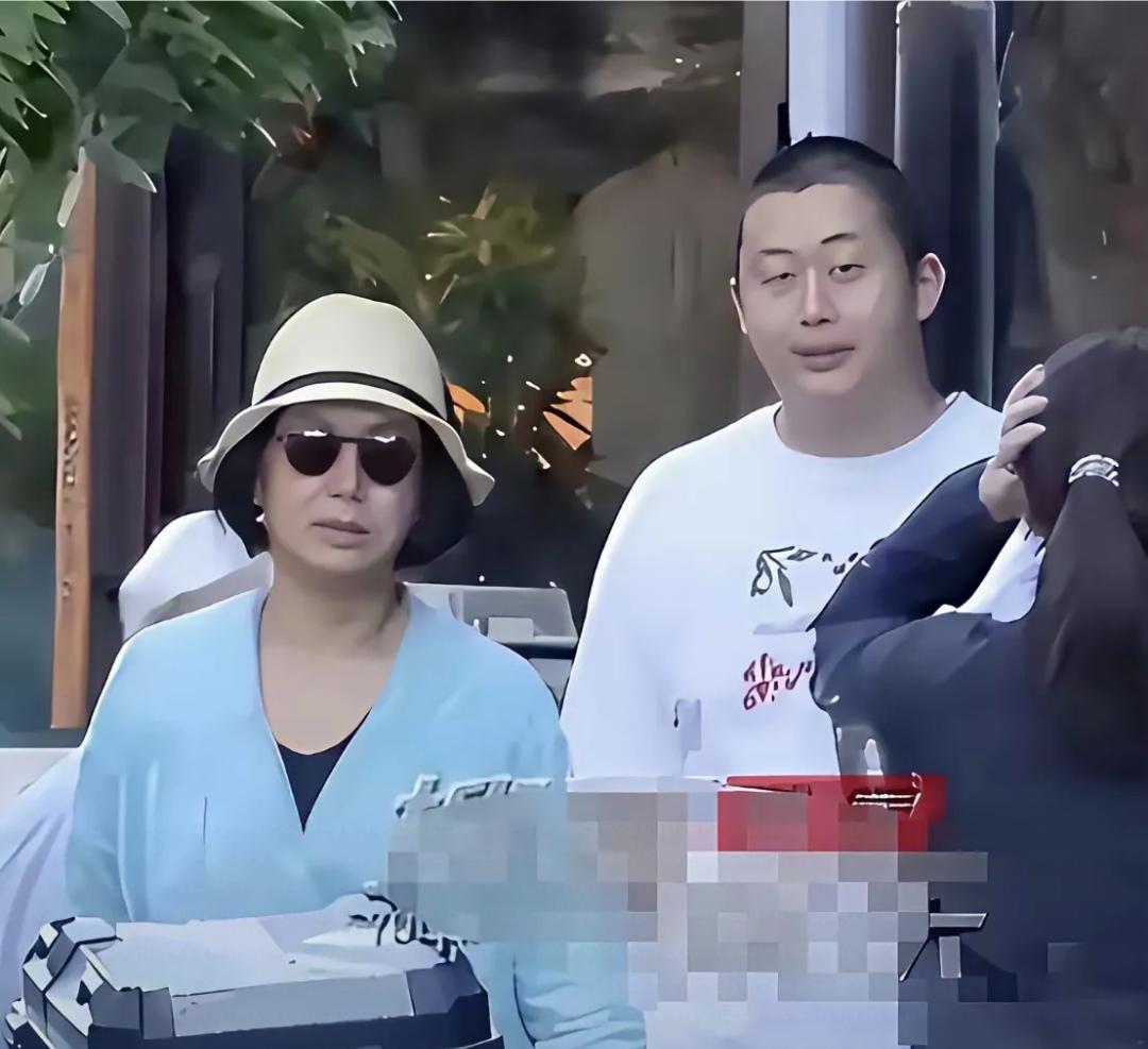 蒋雯丽一家现身英国街头，将雯丽穿着浅蓝色裙子，黑丝袜，戴着墨镜，帽子，大步向前走