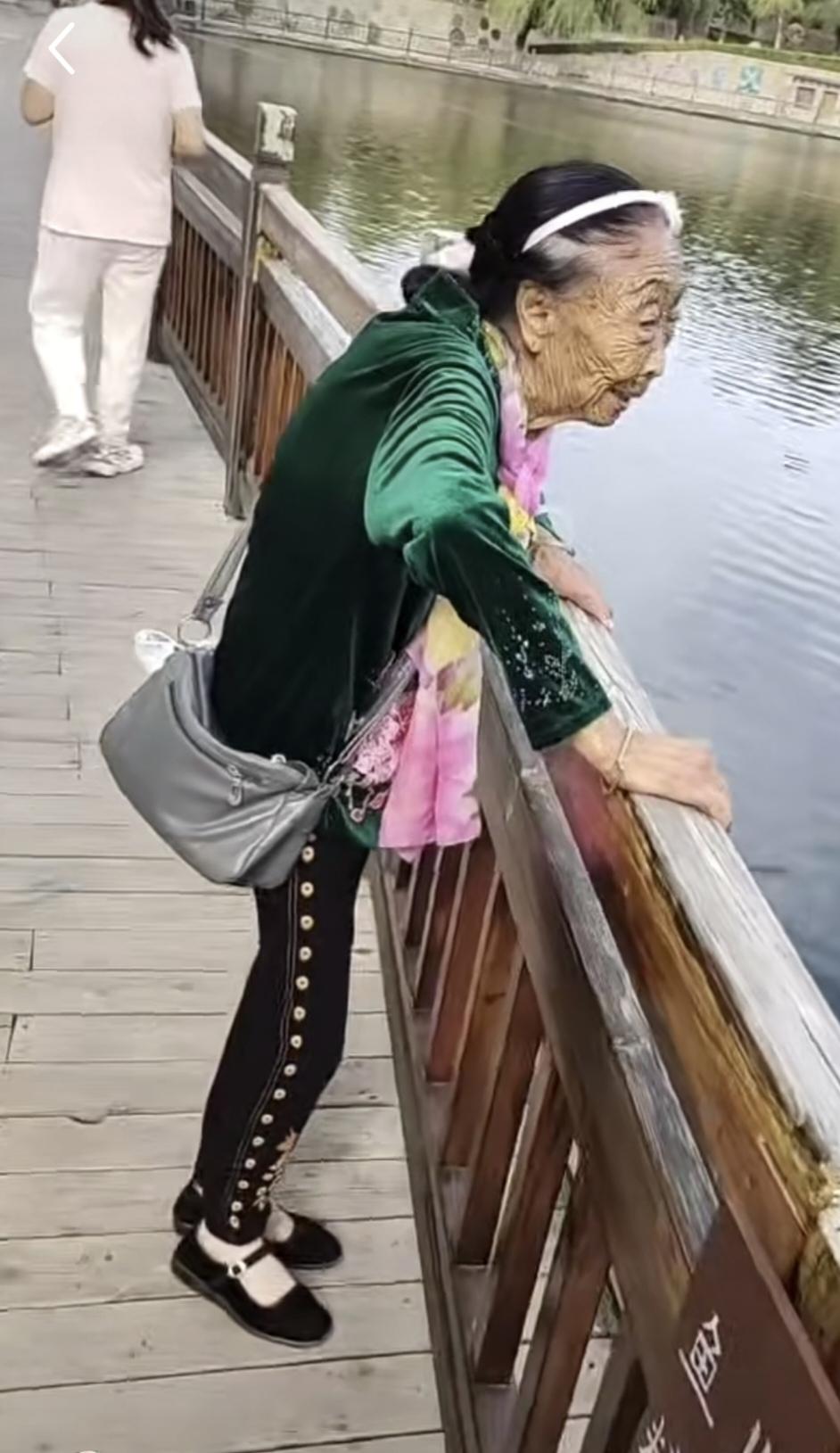 马玉琴打扮得利利索索的，来河边游玩观鱼来啦：绿袄，黑裤，布鞋。灰色斜挎包很抢眼，