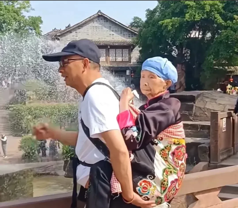 “您背我长大，我背您到老！”四川成都，一位大叔带母亲去逛景区，为了方便，大叔灵机