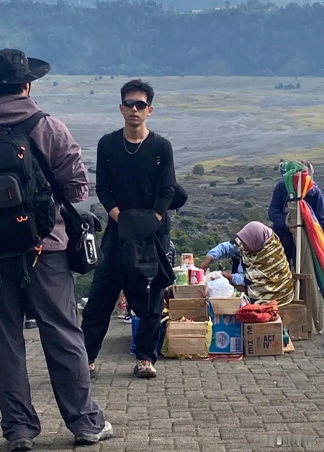 李现现身印尼，他戴着墨镜，头发浓密，肤色有点黑，穿着一身黑色的运动装，背上还背着