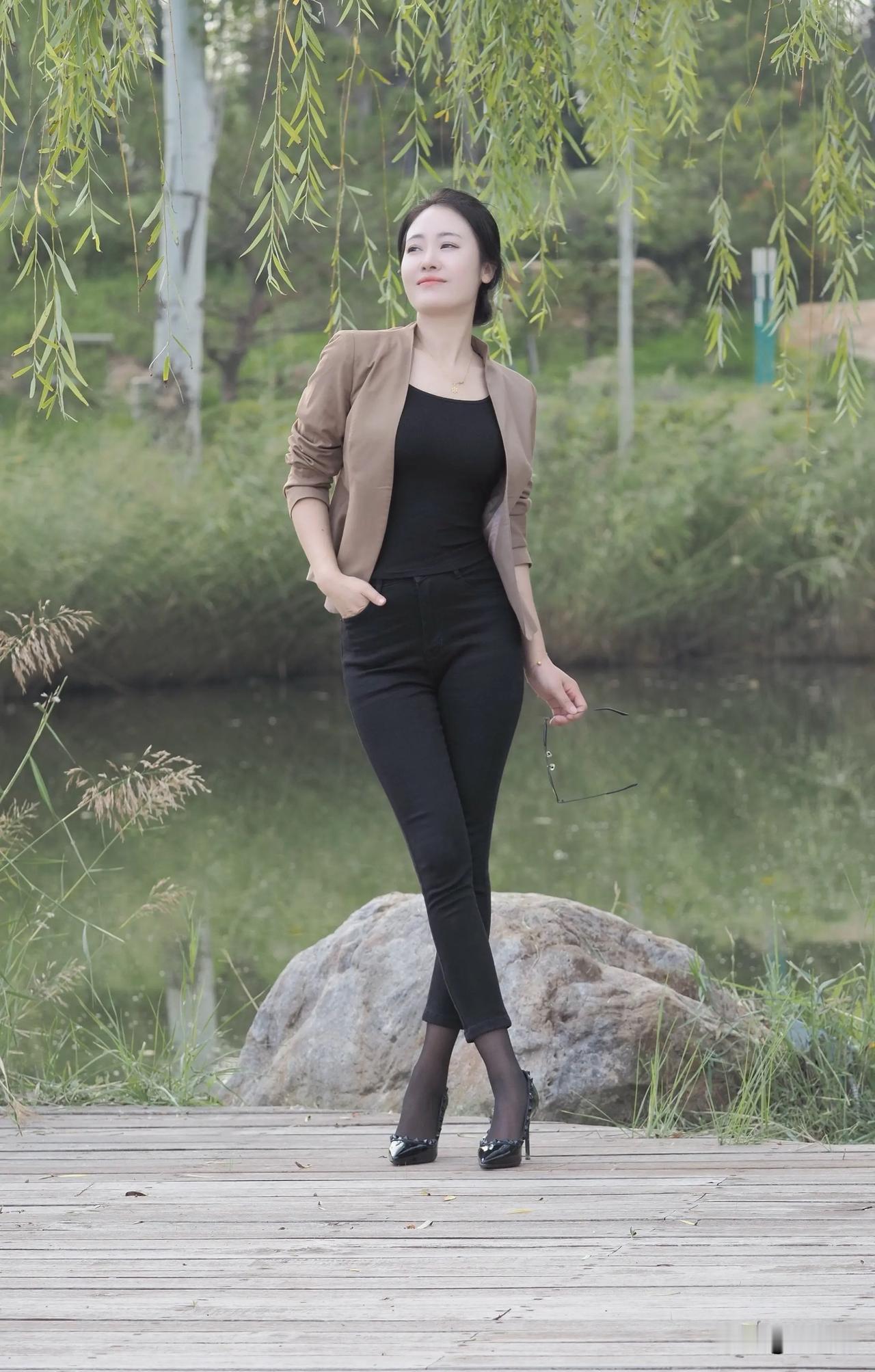 这位女士在湖边散步，穿着时尚。