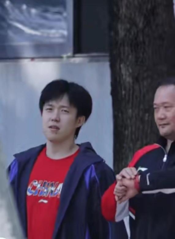 4月9号的王楚钦，一眼看过去就很亮眼，他穿着红T恤，外面再搭一件蓝黑外套，简简单