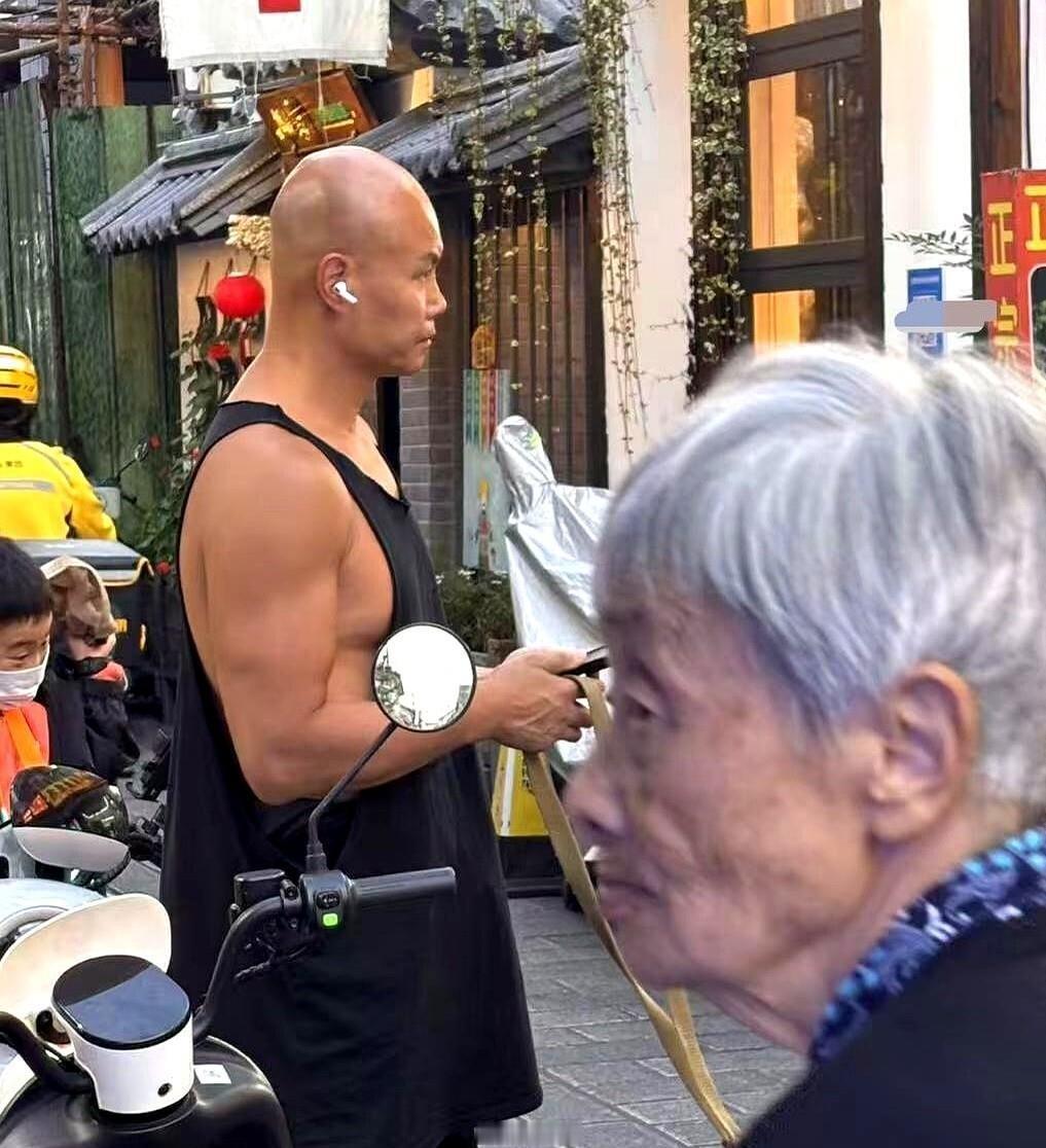 51岁的乐嘉在大理街头被偶遇，骑着一辆墨绿色边三轮，身边跟着一条大狼狗，黑色背心