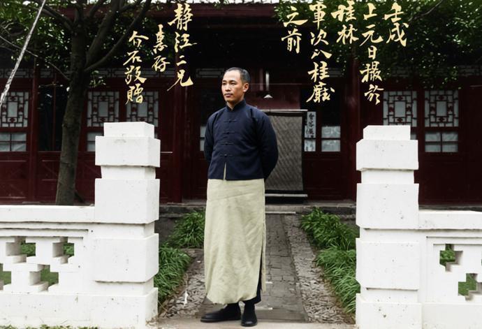 1922年，蒋介石身着传统长袍马褂，双手背后，站姿端正，面容清瘦、表情严肃，整体