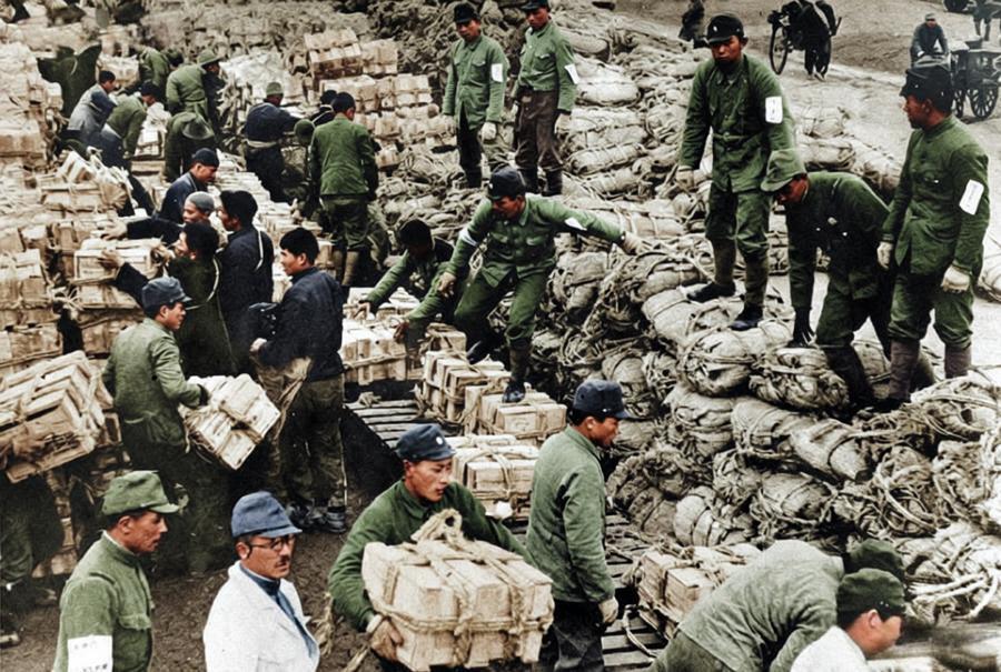 这是日军侵占东北期间掠夺物资的现场，照片中成山的包裹、箱装食品堆在空地上，日军士