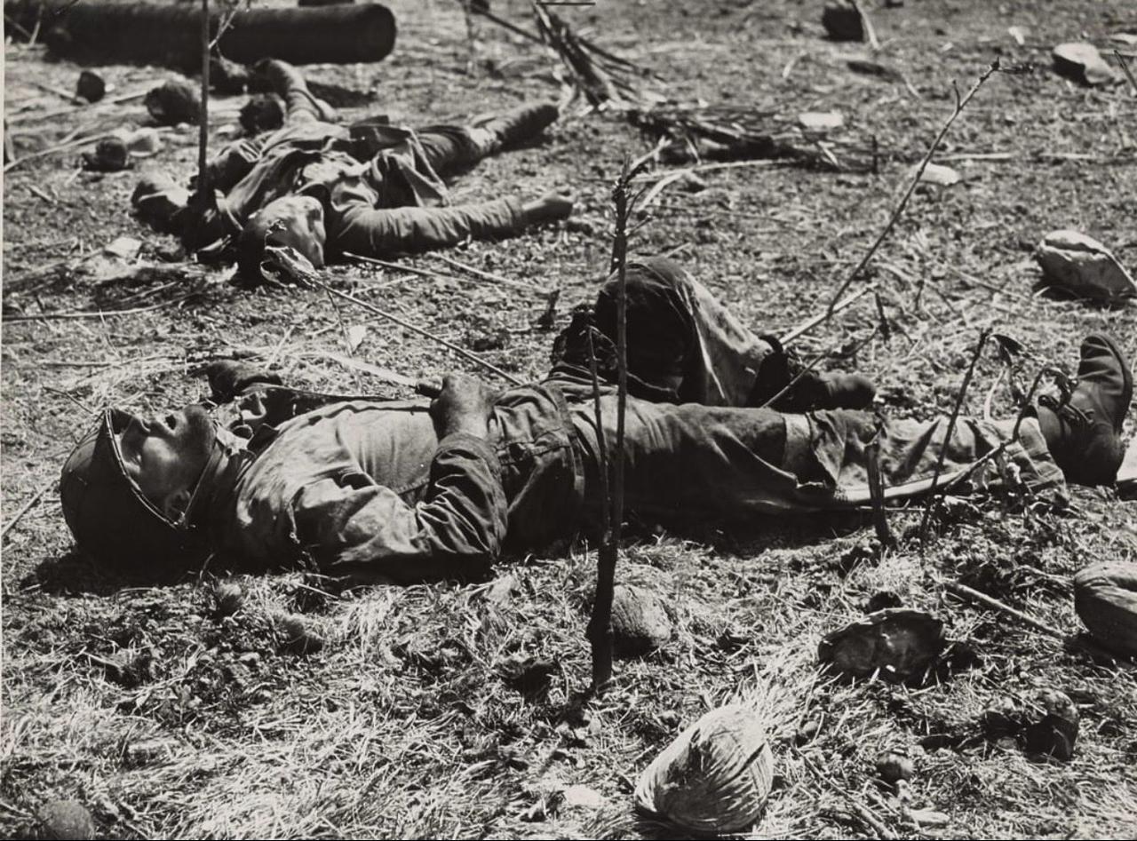 1944年2月照片前景中，一名美国海军陆战队员仍紧握着他用来在埃尼威托克环礁恩格
