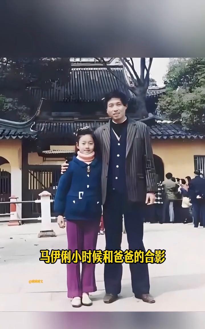 马伊俐小时候和爸爸的合影，爸爸长得高大帅气，爸爸穿着灰色的西装，那个年代能穿上西