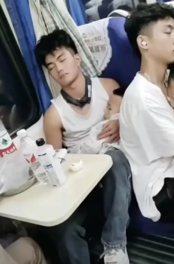 硬座车厢里，一位年轻妈妈带着两个孩子，疲惫地站在过道上，两名准大学生男孩，一个举