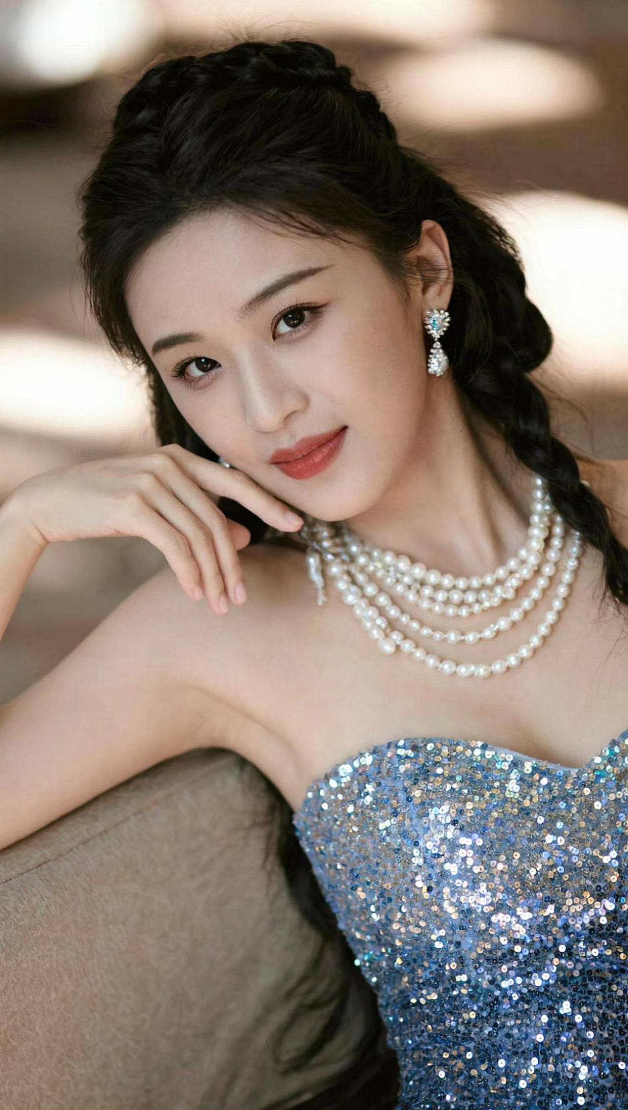 在璀璨的珍珠项链下，藏着一颗温柔的心。优雅的蓝色礼服如同夜空般深邃，诉说着无声的