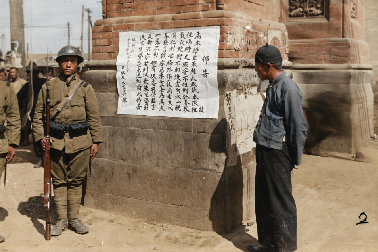 1931年9月，九一八事变后，奉天，一名持枪的日本宪兵，守卫着石柱上一张写满谎言