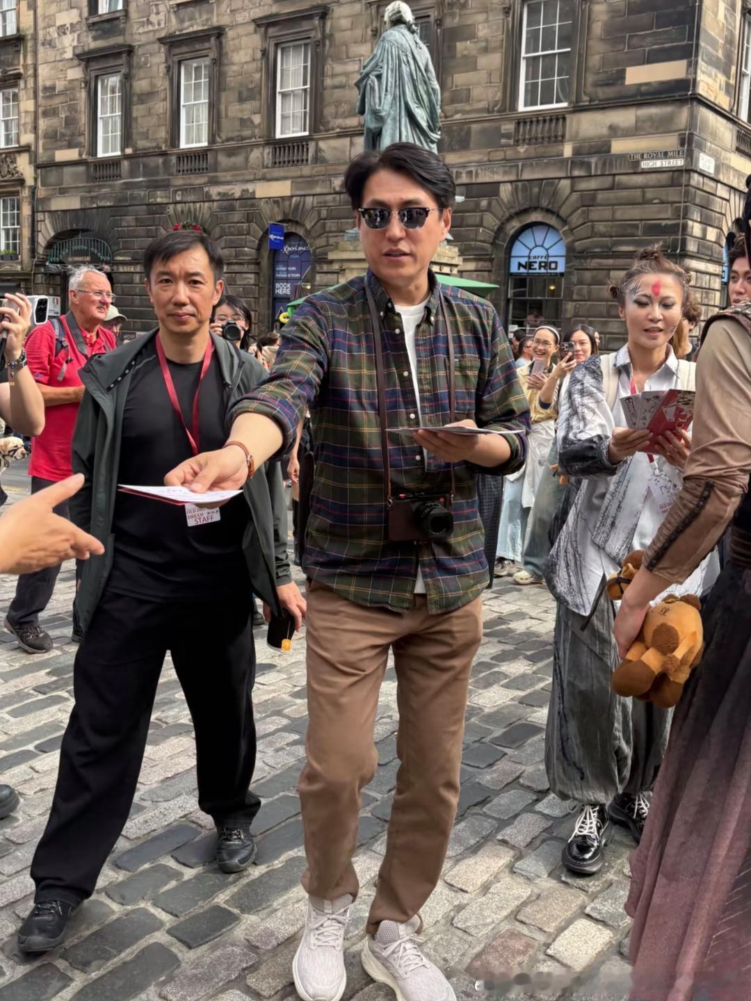50岁靳东现身英国街头，他穿着格纹衬衫，戴着大墨镜，身姿挺拔，身形微胖