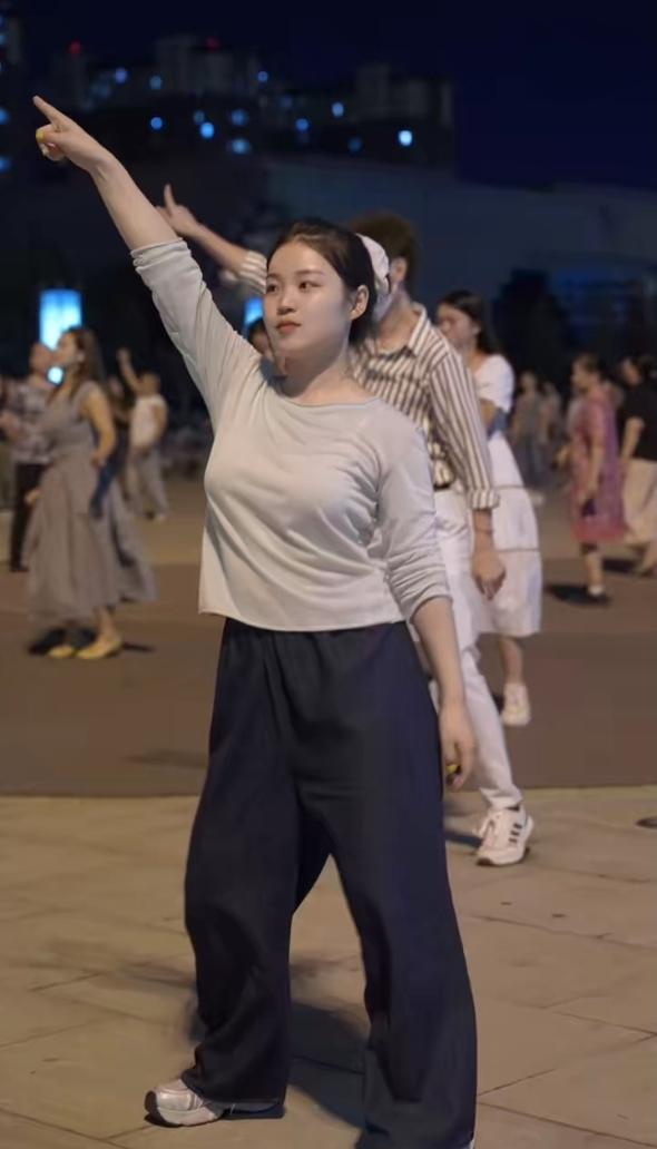 女孩跳广场舞行云流水，姿态优美。