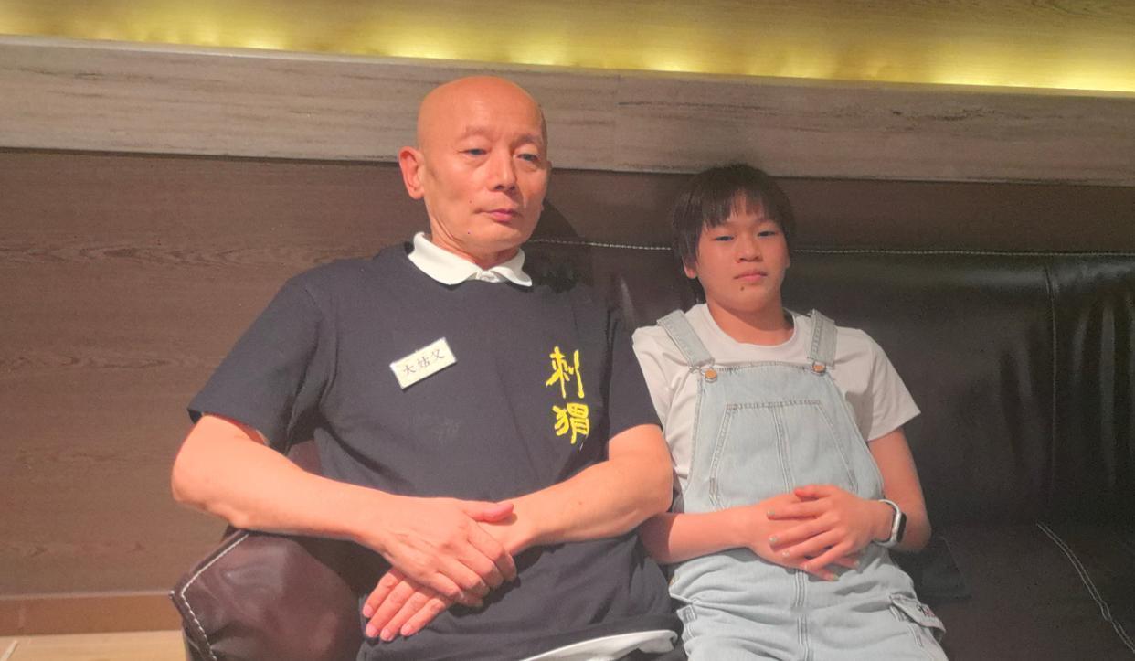 全红婵与葛优同框：穿着牛仔背带裤的全妹柔发覆额，粉面含春，目光低垂，涂着蓝灰色的