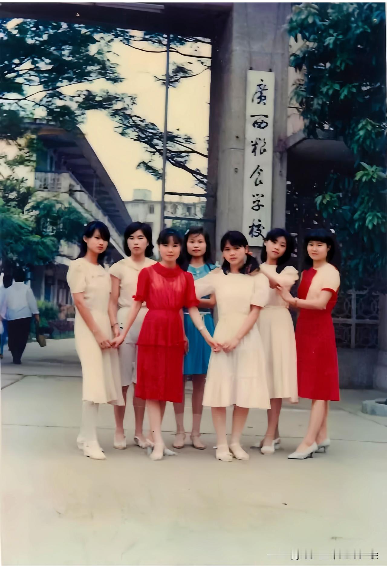 一九八八年，广西粮食学校中专即将毕业的七位女学生在校门口牌匾前的合影老照片。照片