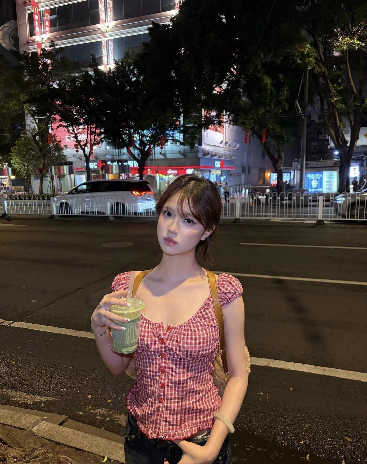 夜晚街头的少女，手捧奶茶，静待归人。