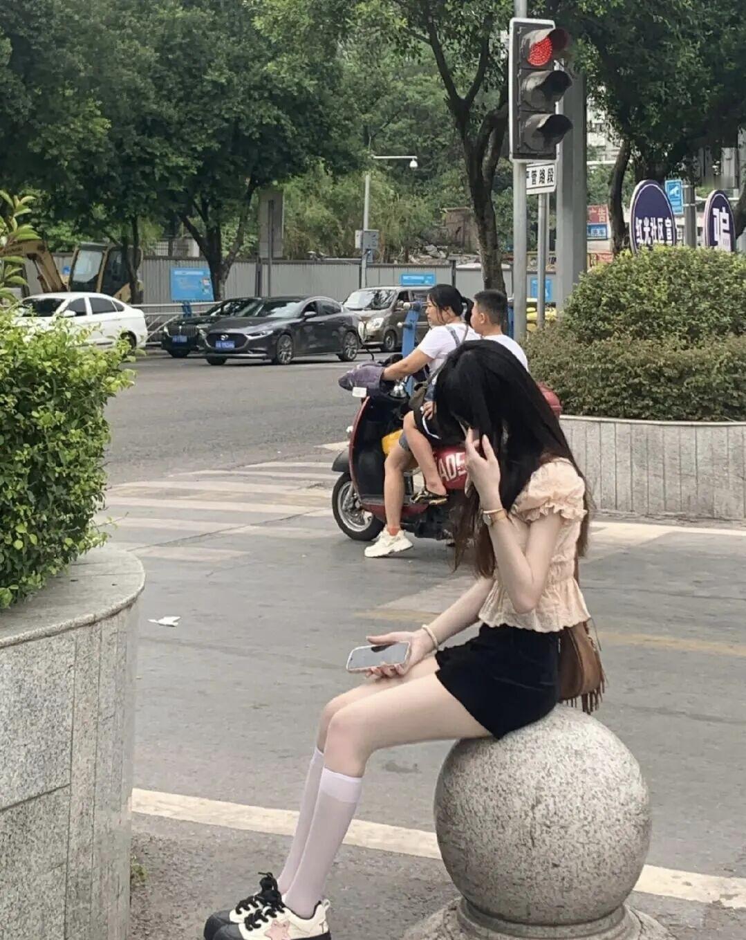 风裹着树影晃了晃。她低头戳着屏幕，流苏包上的HelloKitty跟着裙摆轻摆，