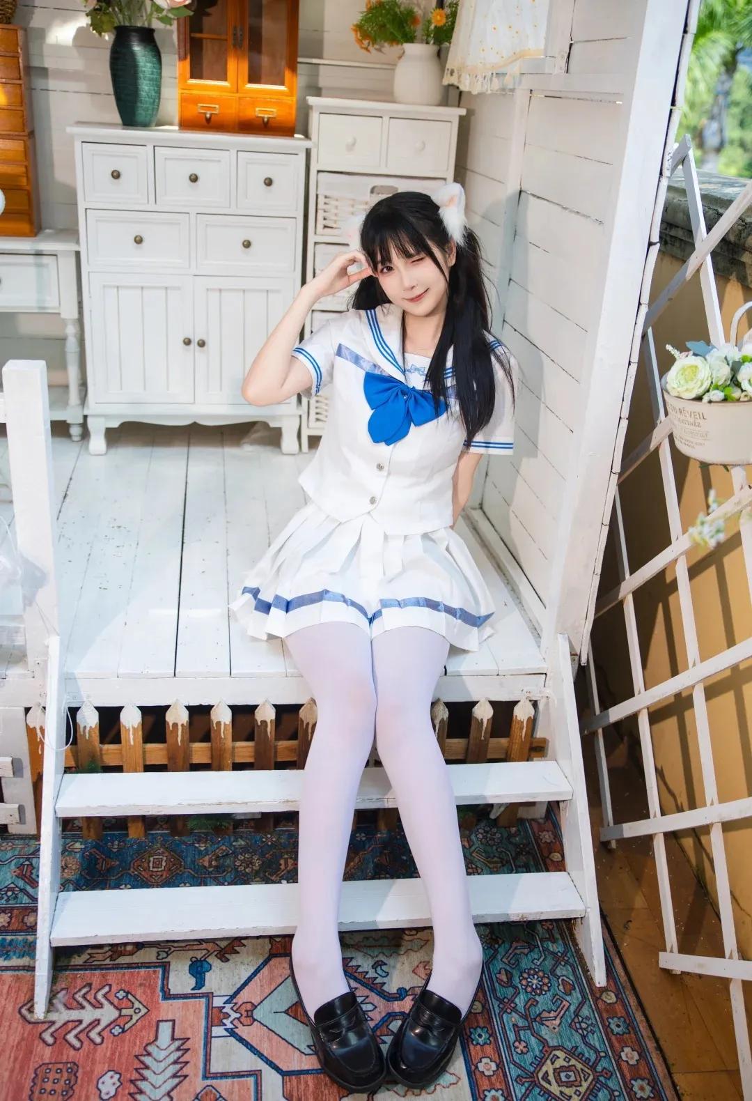 一个女孩坐在楼梯上，穿着水手服。