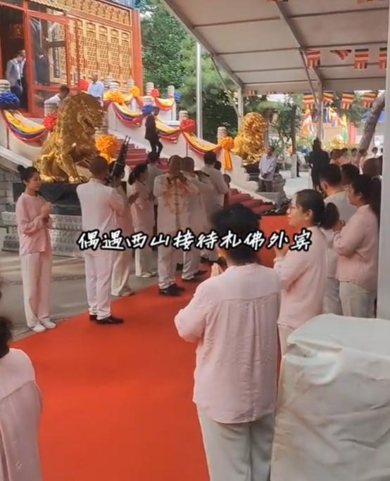 北京灵光寺迎来了贵客！这位贵客就是敏昂莱，他走在红毯上和主持边走边聊，穿着西服很