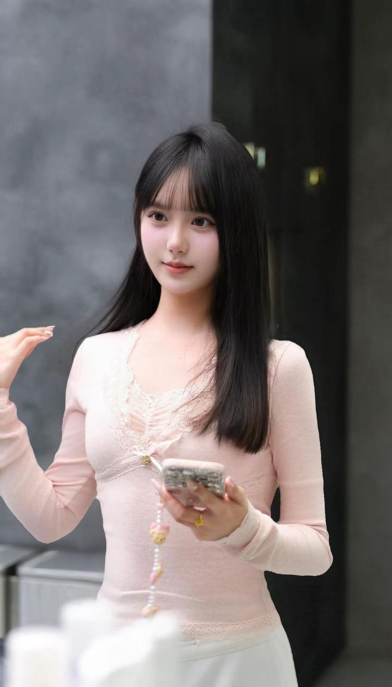 温柔甜美的少女，粉色蕾丝长袖上衣，手机轻触指尖，优雅动人。粉色长袖穿搭温柔粉色