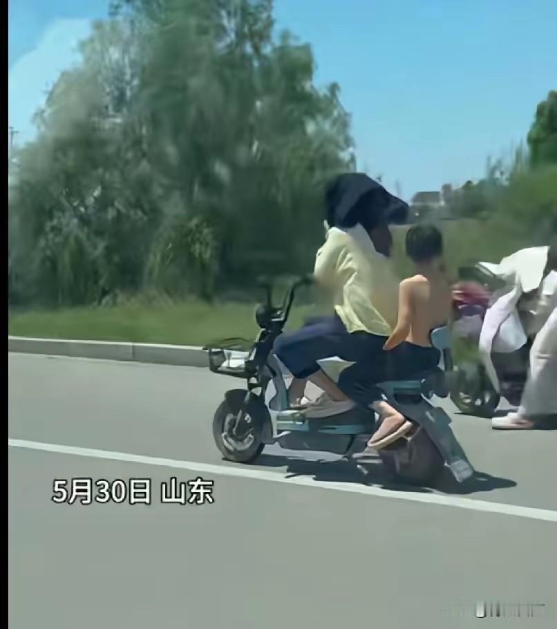 绝对亲生的！5月30日，山东，妈妈骑着电动车带着儿子，因为太阳大，妈妈怕晒，要