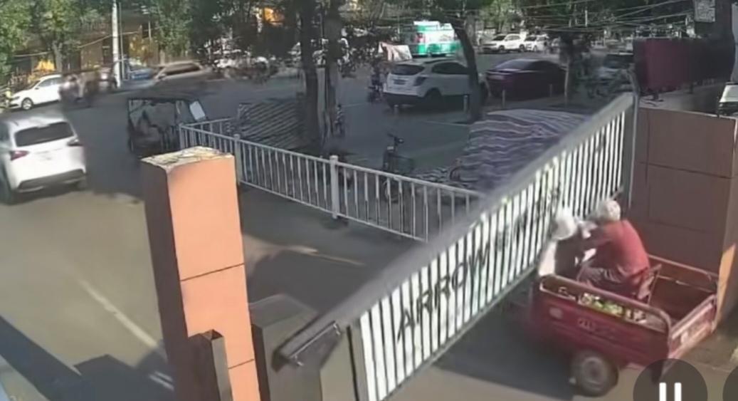 一位大爷骑着电动三轮车，车上坐着老伴，大爷准备出小区办事，看前面一辆白色汽车，到