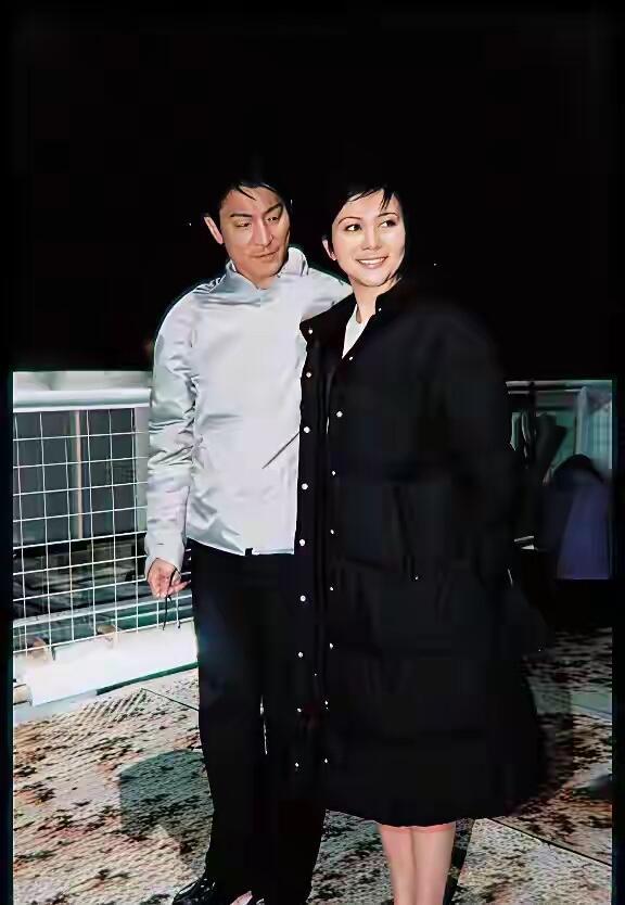 刘德华旁边的这一位美女好漂亮啊，她留着短头发造型，穿一身黑色长款外套，不是电视上