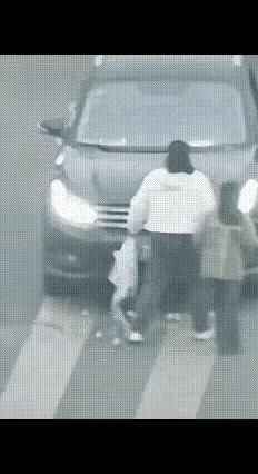 黑色轿车斑马线不礼让行人，撞破了女子的水果袋，水果掉落一地。司机下车不仅不道歉还