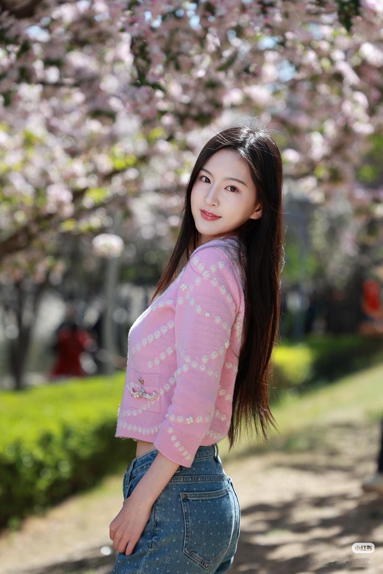 粉衣美人倚树旁，花影摇曳映笑颜。