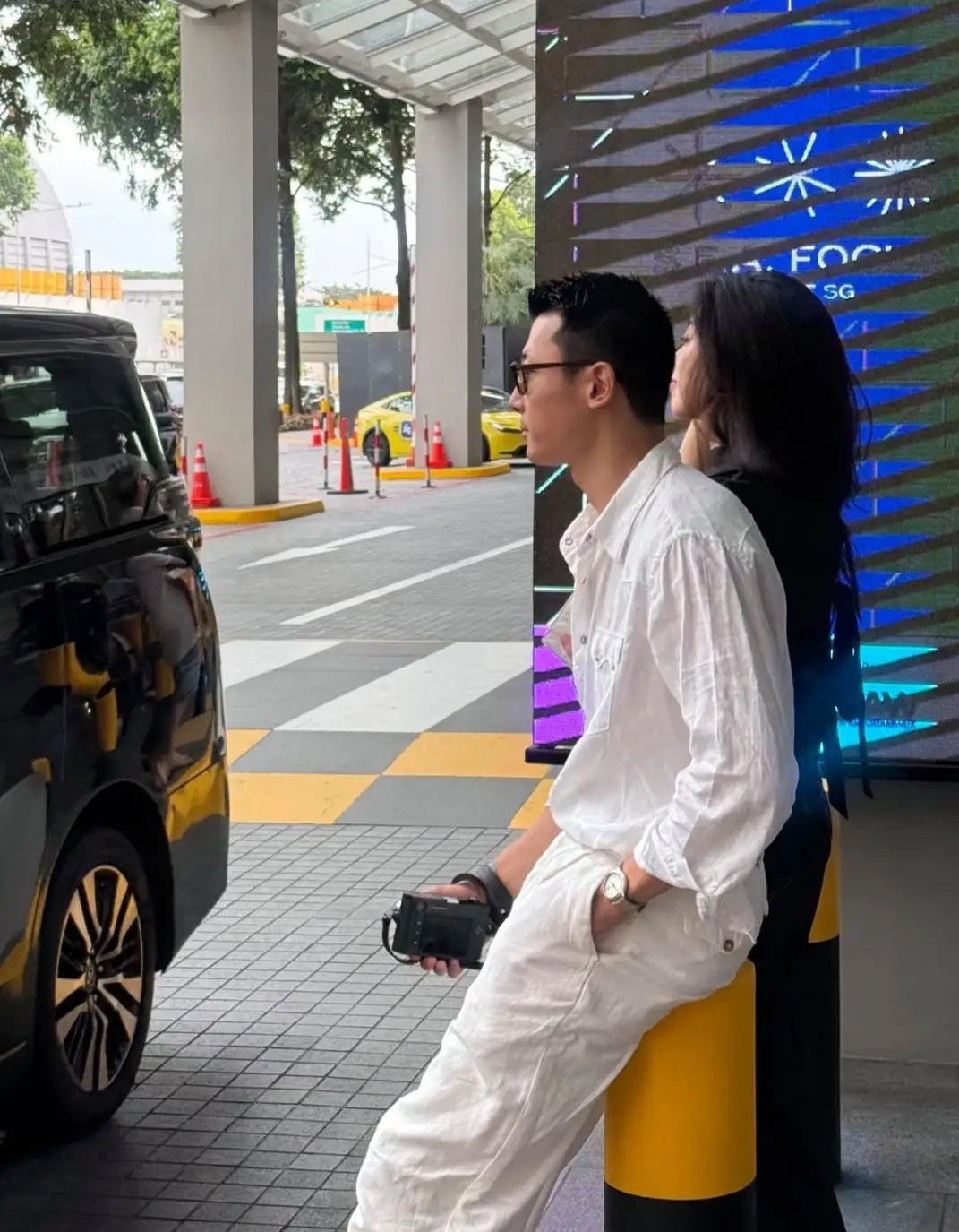朱珠和老公王昀佳现身新加坡，两人在路边等车，夫妻俩穿着一黑一白的衣服，看起来好时