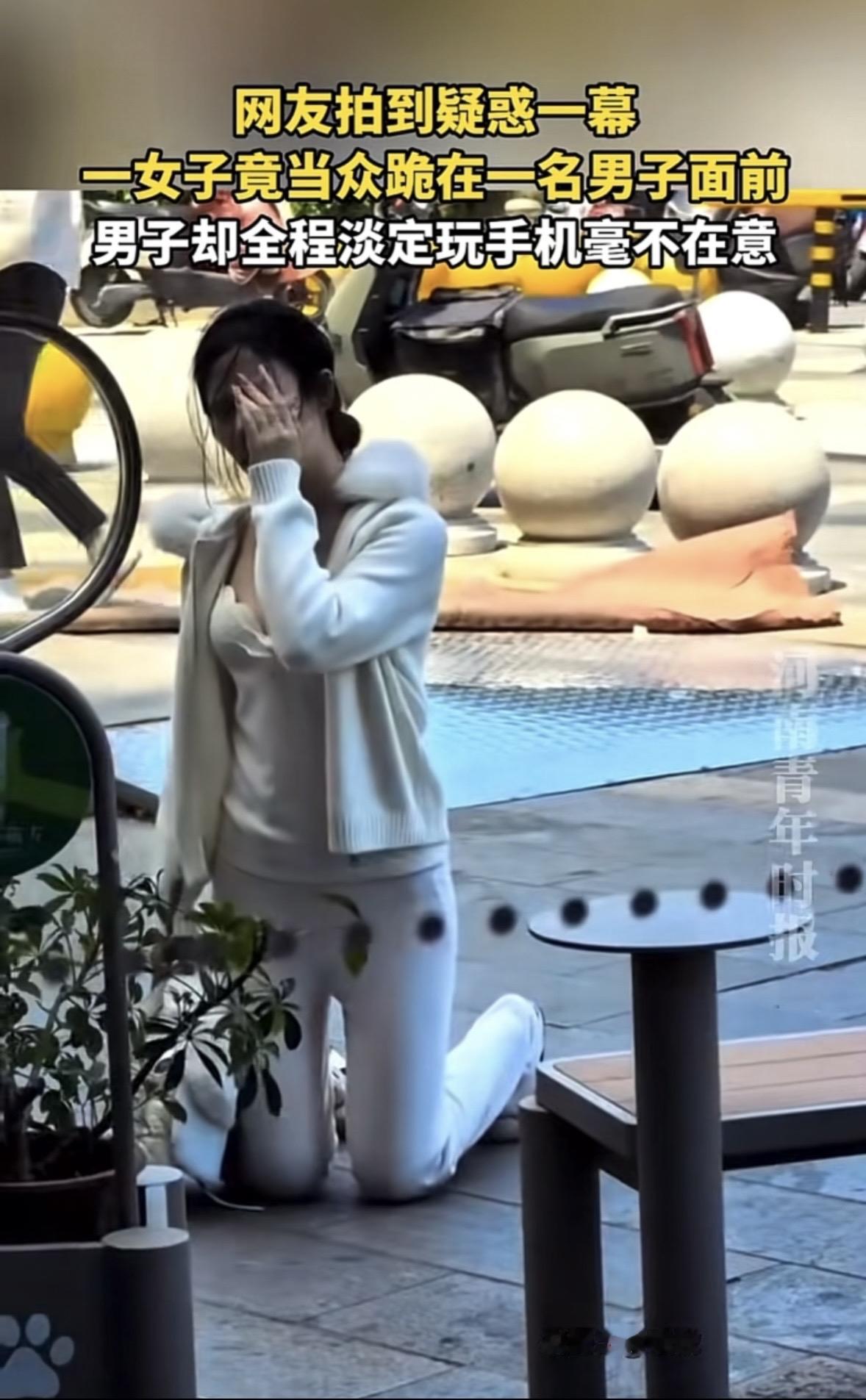 上海，一名白衣女子当众跪在一男子面前，哭得梨花带雨，而她对面的男子坐在椅子上，全
