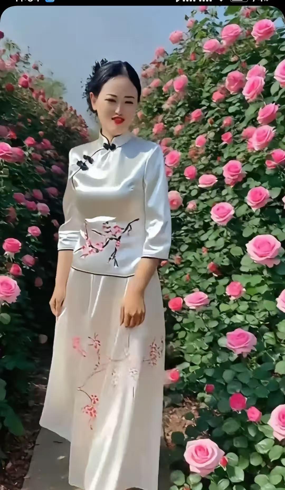 水仙子·旗袍赏玫旗袍轻裹韵如弦，梅影匀来色染鲜。繁花夹道娇容现，似春云映