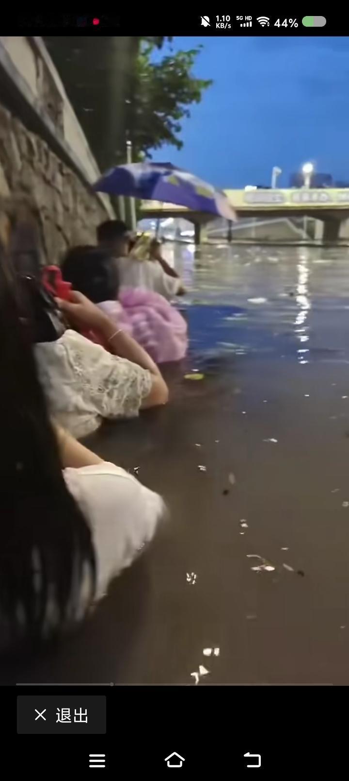 这什么心理？——网上视频：某地，大雨，一群人水中前行，水早已过腰，有人拍照，或