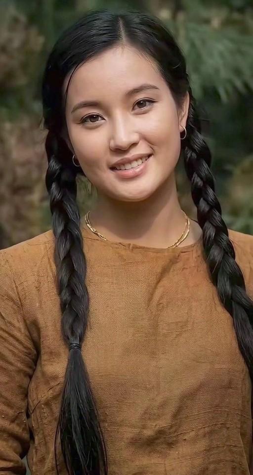 这是年轻时的刘晓庆，两条乌黑粗长的麻花辫质朴动人，笑容明媚鲜活。一身朴素粗布衣衫