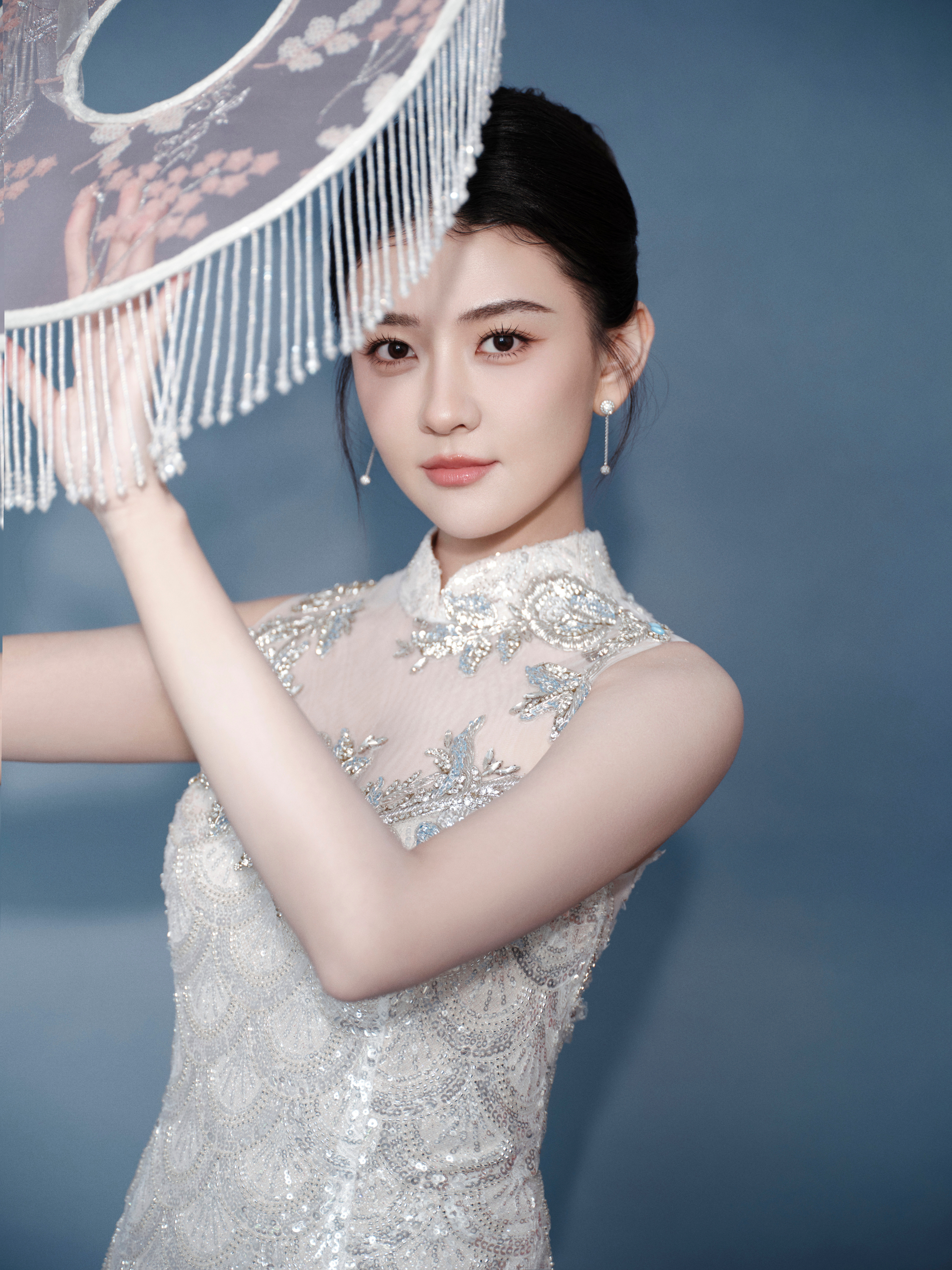 梁洁一袭银白亮片旗袍，勾勒窈窕身段，立领添古典韵，透纱绣花藏诗意。东方美在光影