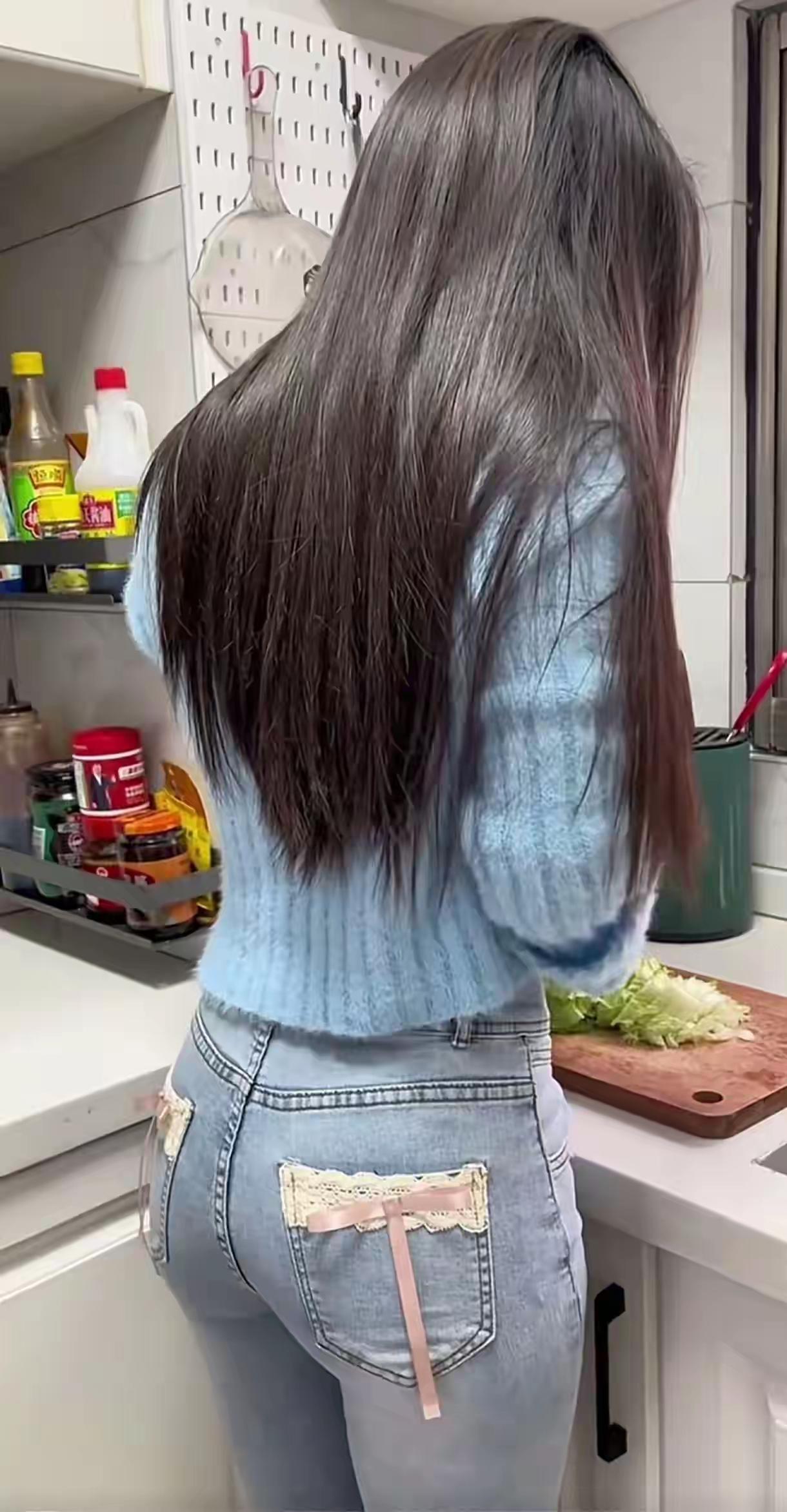 长发垂落肩头，浅蓝色针织衫配带蝴蝶结的牛仔裤，在烟火气的厨房里认真备餐，把普通的