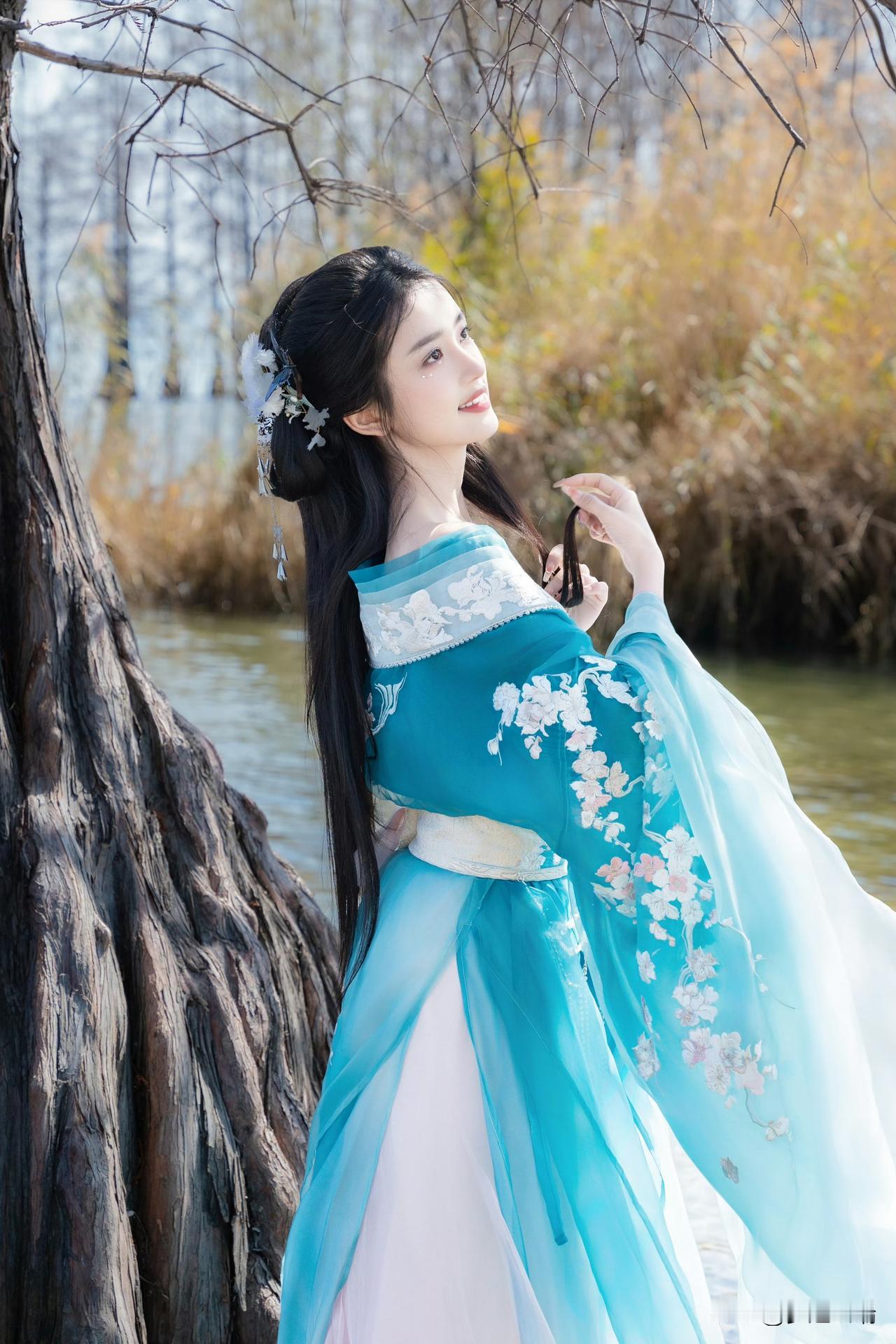 秋日河畔，蓝衣美人倚树轻笑，如梦似幻。