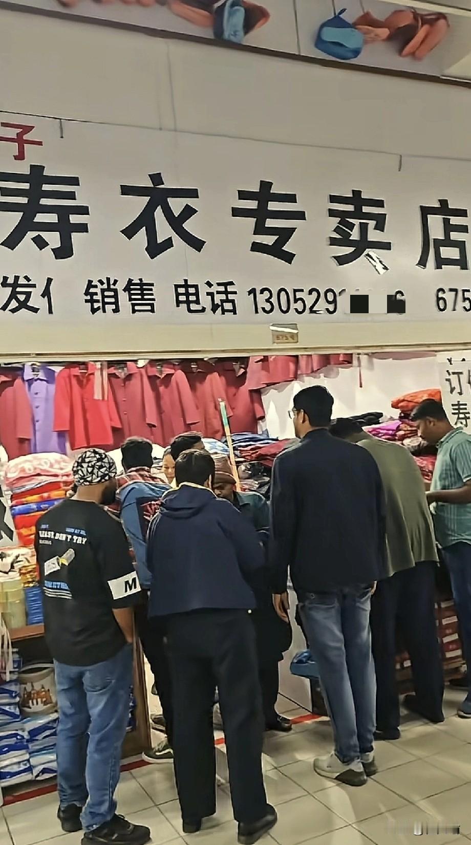 江苏，一家专卖店门口围了一群外国游客，他们对店里的衣服很感兴趣，还拿起来往身上比