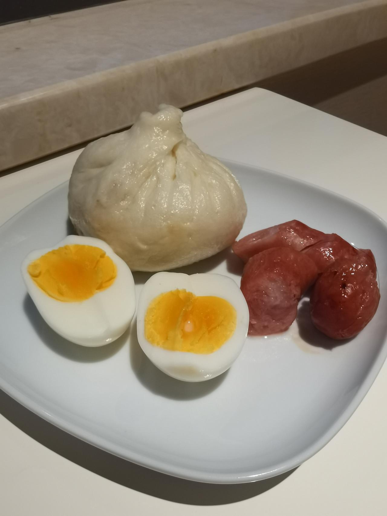 今日早餐：黄瓜丁拌纳豆、一根肉肠、一个肉包子、一个鸡蛋、一杯牛奶咖啡。简