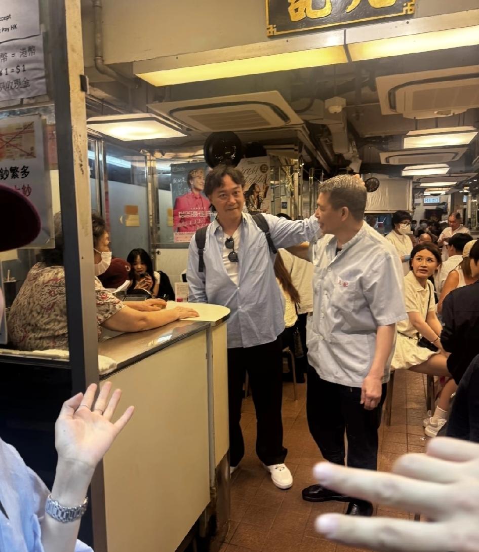 陈奕迅现身香港九记牛腩餐馆吃饭，他和老板现在门口有说有笑，手里拿着手机和粉丝合影
