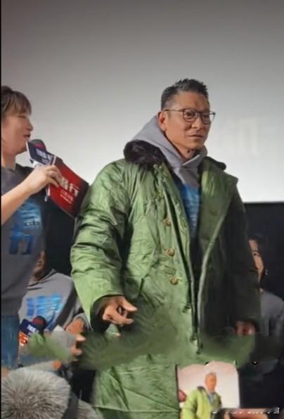 天王刘德华酷爱军大衣，近日，天王刘德华再次穿上橄榄绿军大衣出席活动，军在刘德华