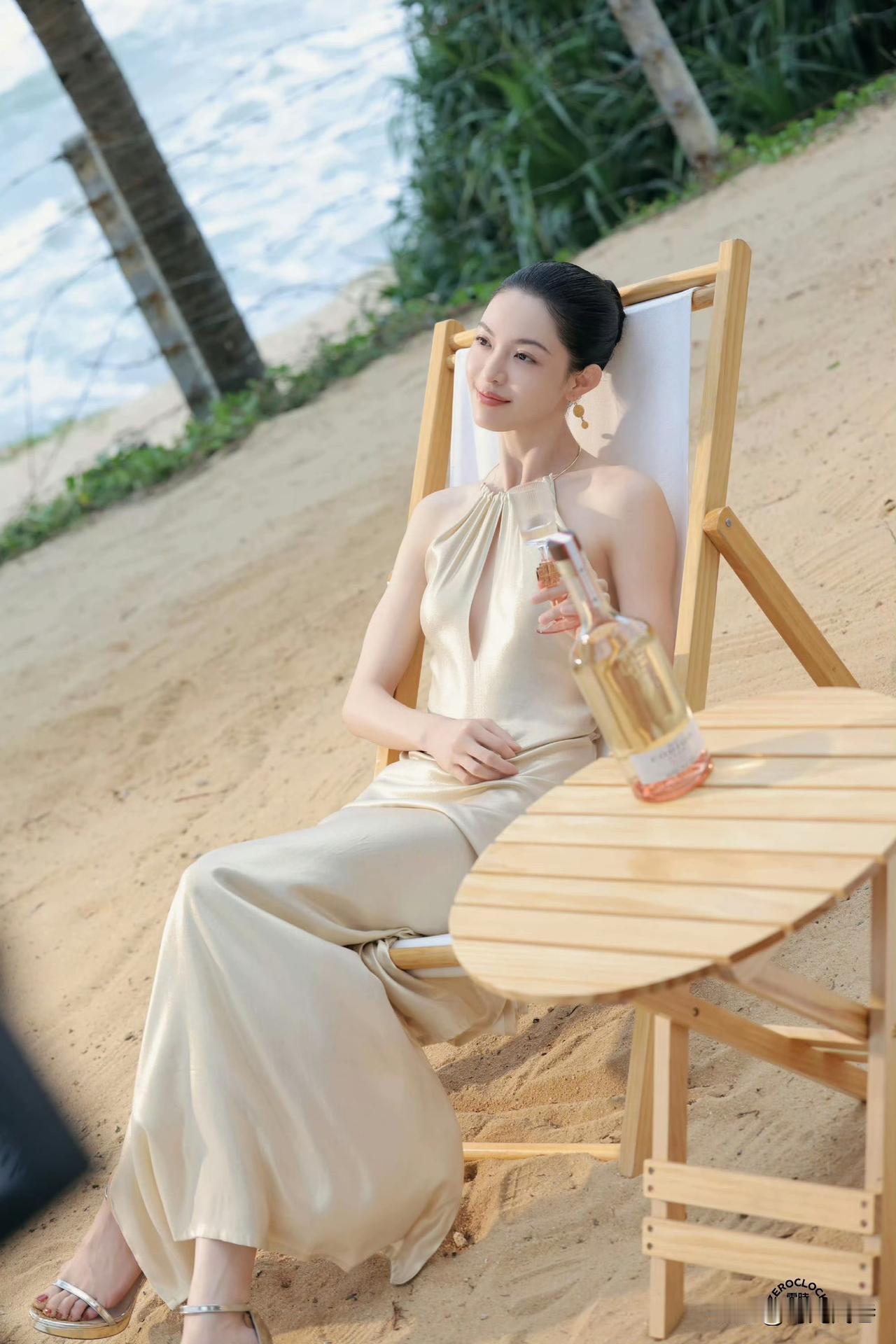 金黄松软的沙滩上，钟楚曦坐在精致舒适的木制躺椅上。静静享受着微微的海风和灿烂温暖
