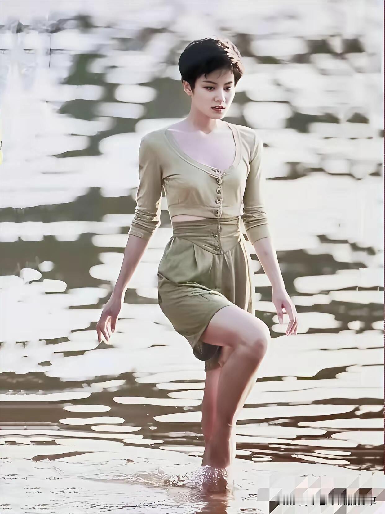 年轻时候的她在海边玩水时留下的一张照片，那时的她留着短发，五官有点硬朗，属于颜值