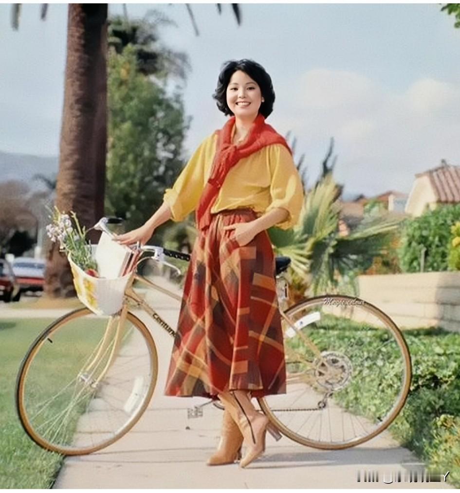 这是一代歌后邓丽君站在一辆自行车旁的留影老照片，拍摄于1980年的美国加州。彼时