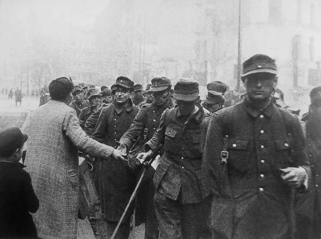1945年5月，柏林，一名妇女向即将被送往苏联战俘营的德国战俘分发香烟……这张照